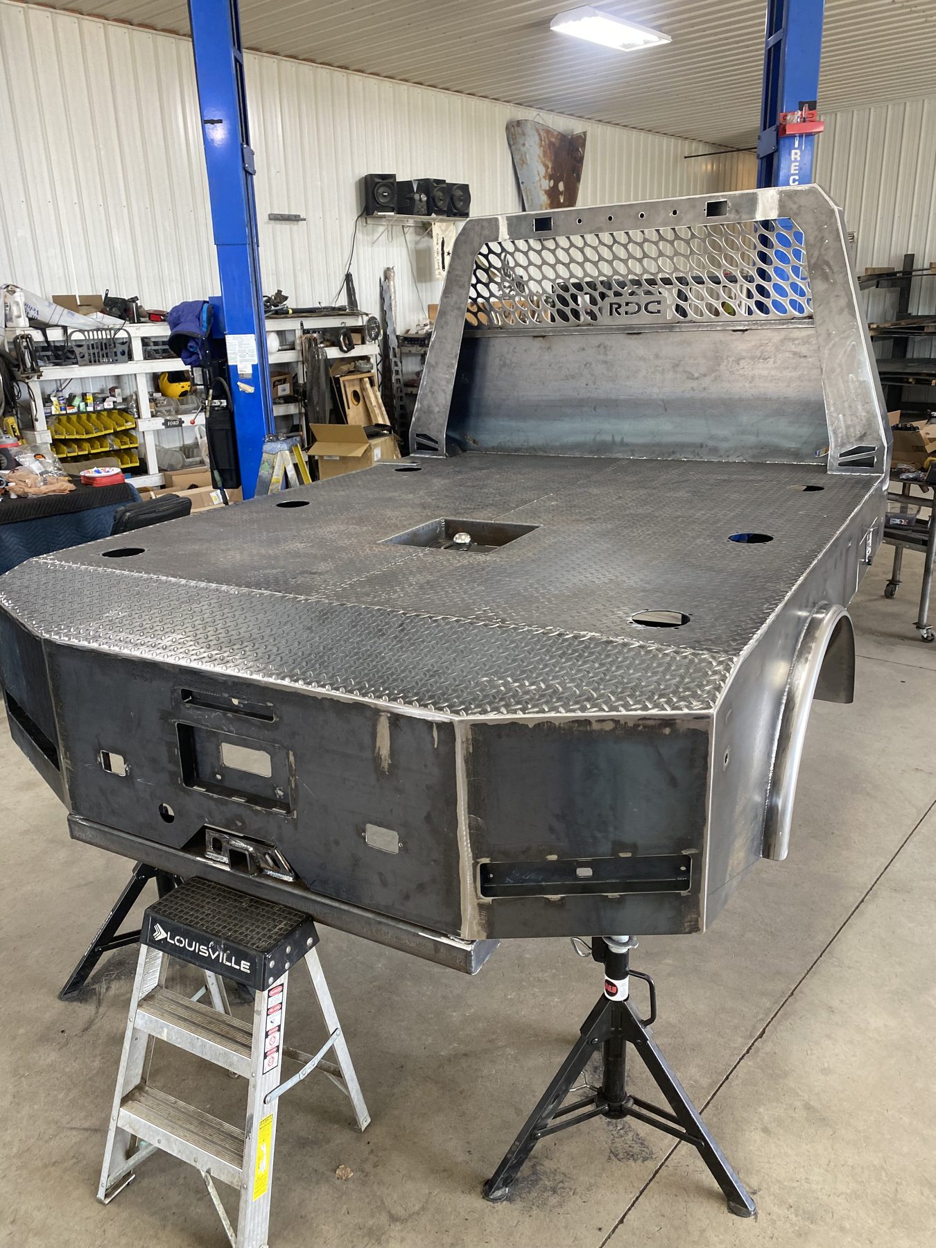 Custom flatbed mid-build showing hex-mesh headache rack