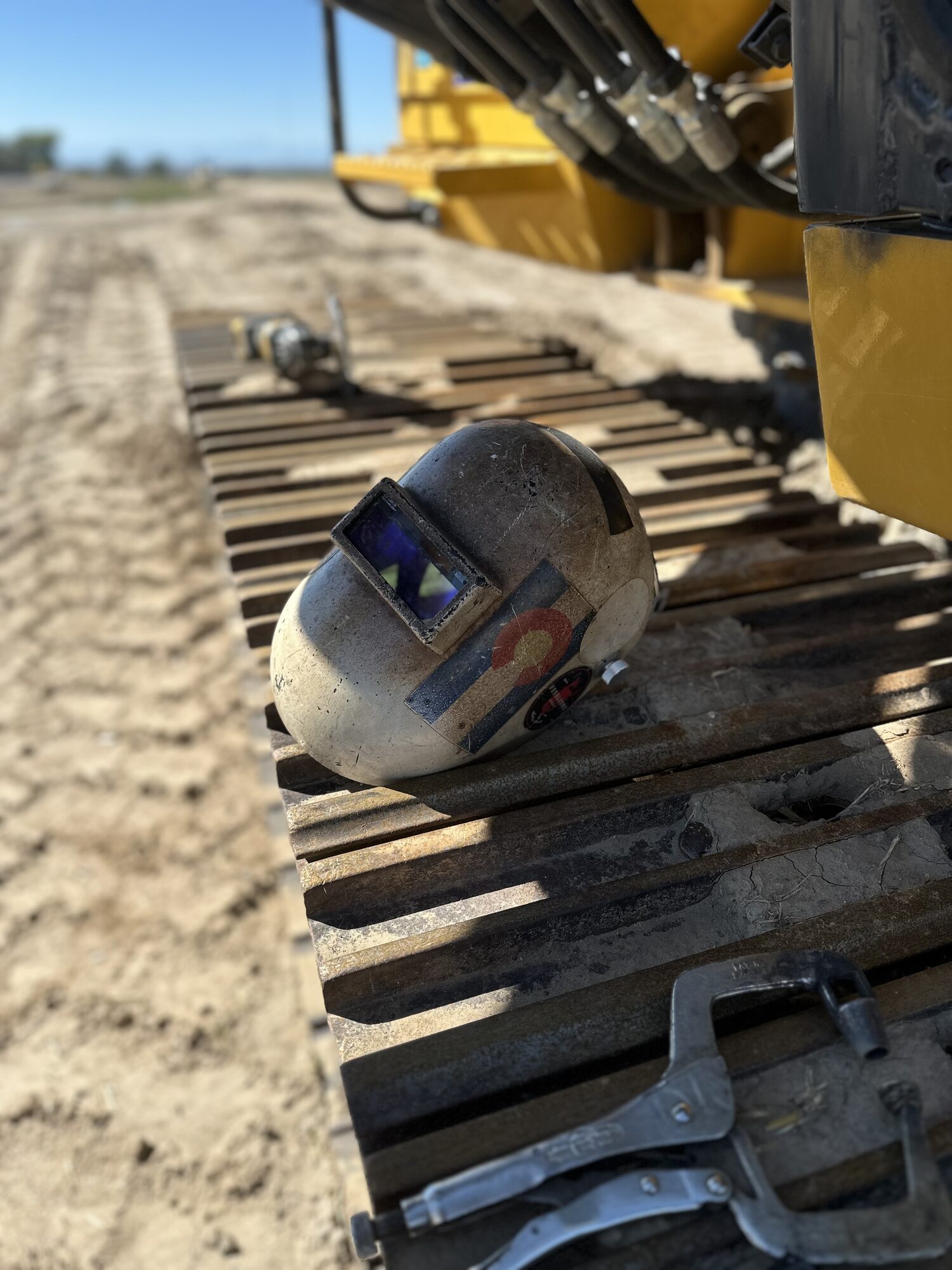ArcWest welding hood resting on heavy excavator tracks at a Northern Colorado jobsite
